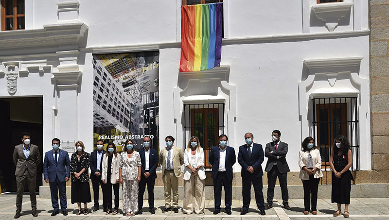 Autoridades regionales delante de la fachada de la Asamblea, de la que cuelga la bandera arcoíris. Foto: Asamblea de Extremadura