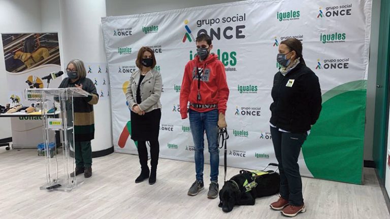 Una persona ciega y sin manos recibe un perro guía de la ONCE. Grada 164. Primera fila